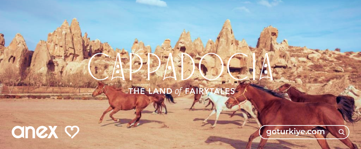 Kapadocja Turcja, pędzonce konie na tle skalnego miasta - Kapadocja